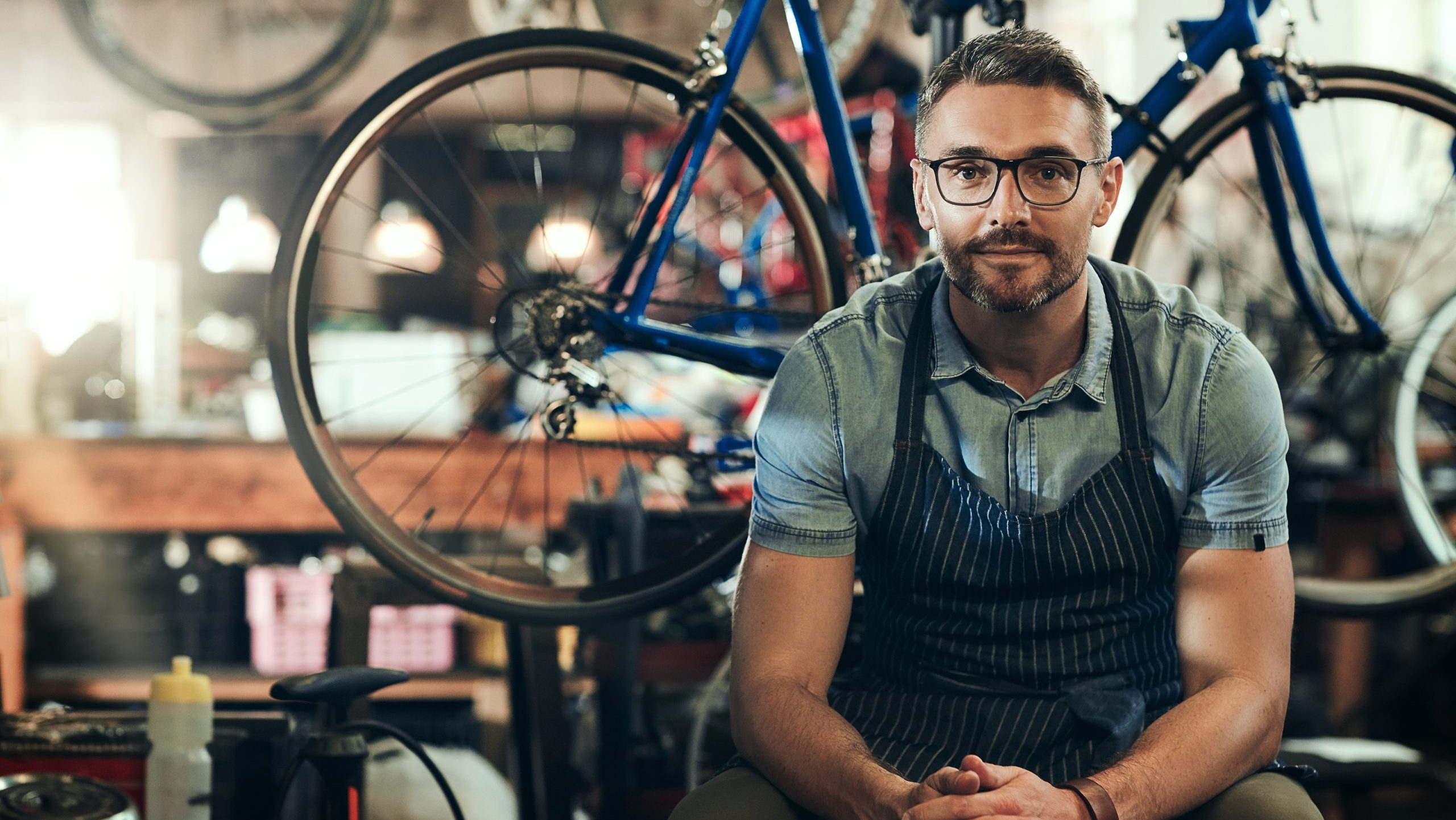 Small business owner repairing a bicycle in his workshop, representing the process of building a strong and professional brand.